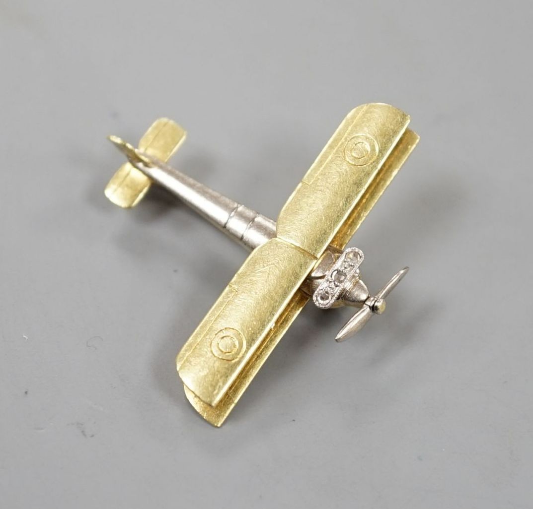 An early 20th century 15ct, white metal and three stone diamond set bi-plane brooch, with revolving propeller, 31mm, gross weight 4.6 grams.